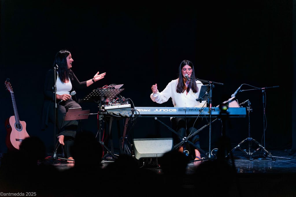 Due musiciste in concerto: una canta e gesticola, l'altra suona la tastiera